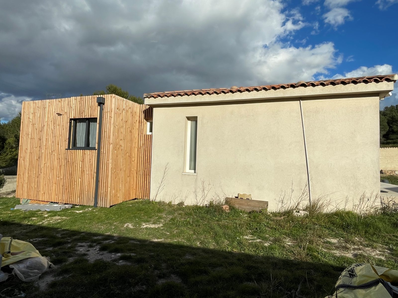 Extension ossature bois à bardage claire-voie greffée sur une maison en crépi — Le Rove