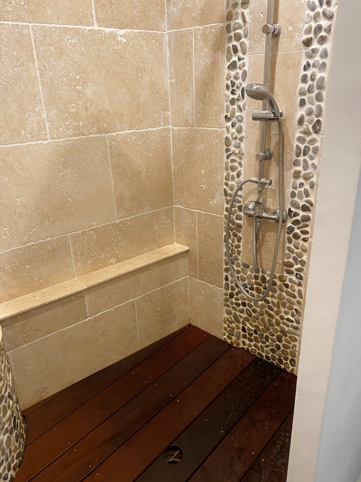 Douche à l'italienne : travertin, galets et caillebotis bois exotique
