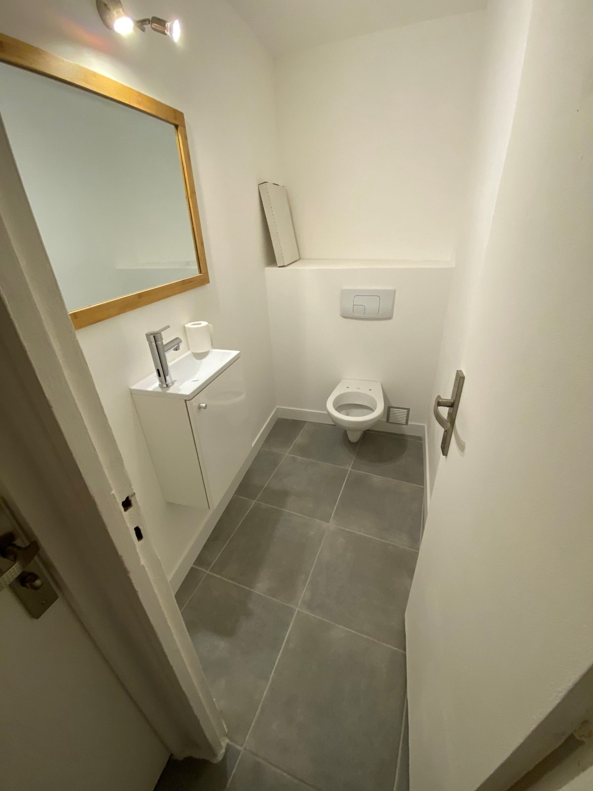 WC rénové : lave-mains, miroir bambou et carrelage gris
