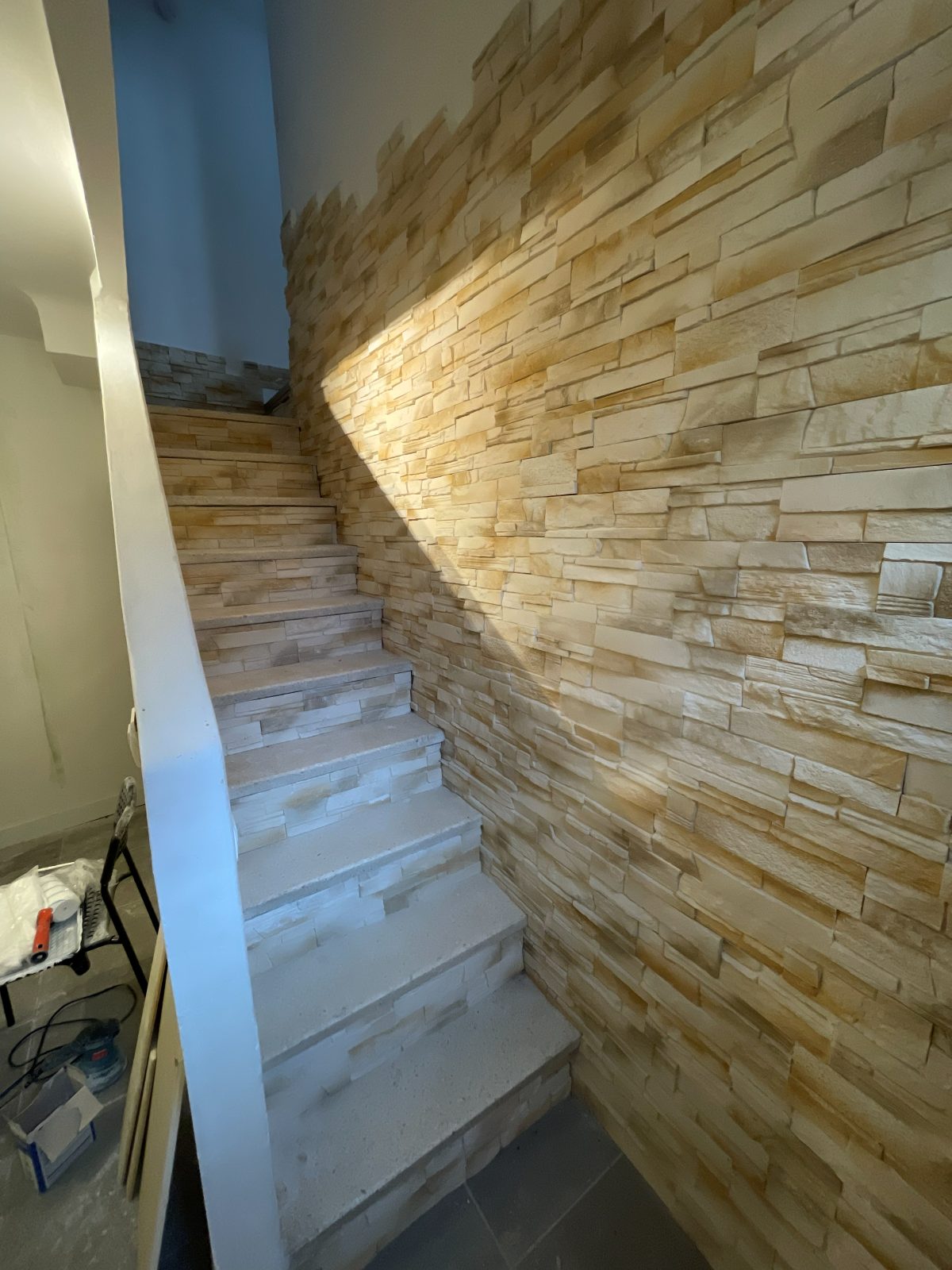 Montée d'escalier : marches minérales et mur en parement pierre